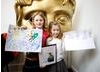 Two workshop participants hold their prize-winning game design and their special prize – a signed LittleBigPlanet picture from Media molecule.