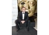 The Coronation Street actor grabs a seat by a BAFTA mask before the show. (Pic: BAFTA/Chris Sharp)